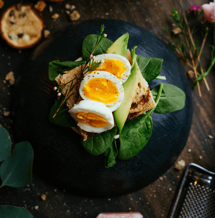 A plate of spinach with toasts, avacado, and eggs present as art.